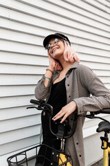 Happy beautiful smiling teenager girl with glasses in fashionable casual outfit with a bicycle...