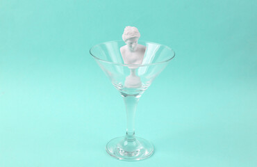 Plaster bust of venus in cocktail glass on blue background. Fresh idea. Minimal party concept, creative layout