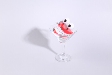 Toy jaw in cocktail glass on gray background. Fresh idea. Minimal party concept, creative layout