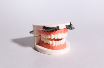 Jaw with false eyelashes on a gray background. Minimal beauty concept