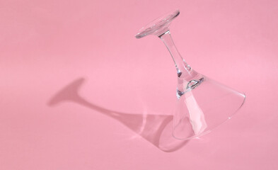 Levitating cocktail glass on pink background with long trendy shadow. Minimal party layout