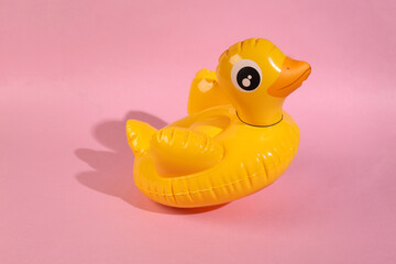 Levitating inflatable duck on a pink background. Minimal layout