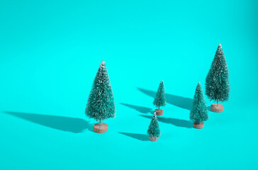 Mini Christmas trees on a turquoise background with long shadows