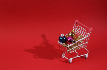 Mini shopping cart with christmas toys and garlands .on red background