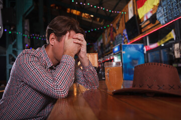 Depressed cowboy man drinking alone at beer pub, copy space