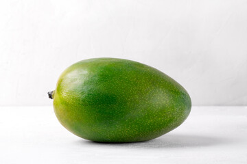 Whole green mango, Keitt variety, on the white table