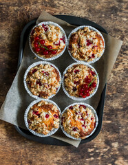 Red currant mini cakes with lemon crumble on a wooden background, top view