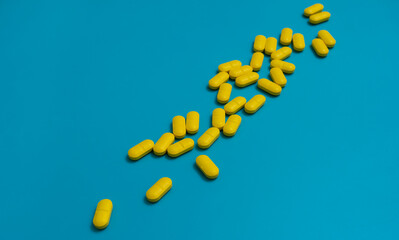 Yellow vitamins medicine capsules pills isolated on blue background.