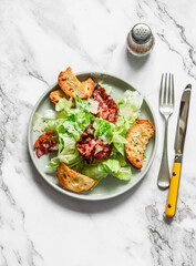 Alternative caesar salad with bacon on a light marble background, top view