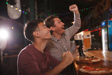 Excited men watching match at beer pub