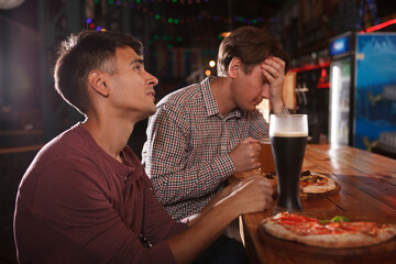 Two man looking sad after watching a game at beer pub