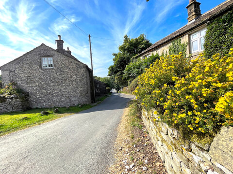 Yorkshire Dales rural scene, with old stone cottages, flowers, and a blue sky near, Kilnsey, Skipton, UK
