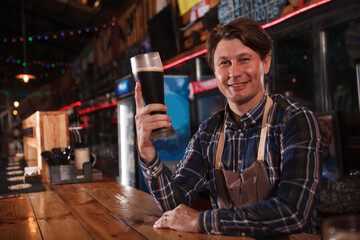 Cheerful brewer serving craft beer at his pub, copy space