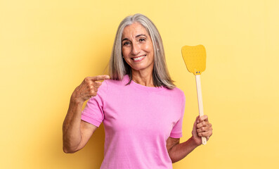 smiling cheerfully, feeling happy and pointing to the side and upwards, showing object in copy...