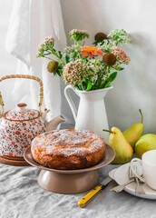Pears pie  and powdered sugar, bouquet of flowers, teapot - served set table for tea