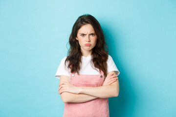 Portrait of angry and upset sulking girl, pouting about unfair situation, frowning and staring at...
