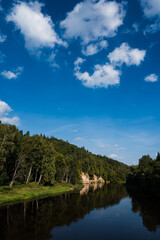 Scenic landscape of steep sandy cliff shore and green trees on it. River Gauja. National park near Sigulda in Latvia.