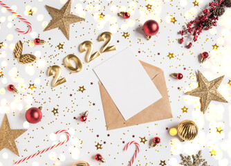 Obraz na płótnie Canvas Open brown envelope with blank white card and numbers of 2022 for the coming year and festive seasonal decorations