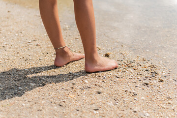 Fototapeta na wymiar rear view of feet and legs walking on the river beach.