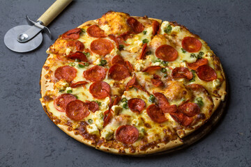 Delicious pepperoni pizza made with salami, feta, chile peppers  on black concrete background. Top view of hot pepperoni pizza. With copy space for text. Flat lay