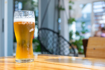 beer in a glass on a brown table with a blurry background