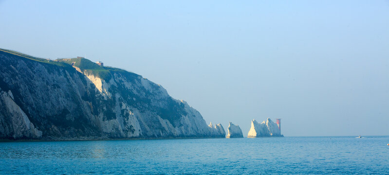 The Needles Lighthouse and White Cliffs of Allum Bay in the Isle of Wight with a hazy bright blue pale sky