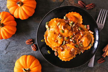 Pumpkin filled ravioli pasta with nuts and pumpkin seeds. Table scene, above view on a dark...