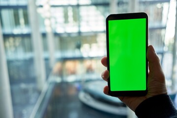 Hand holding mobile phone with chromakey green screen in modern office, walking, moving.