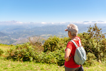 senior woman hiker contemplates the landscape from the top of a mountain