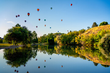 Colorful balloons float over a pond in Boise City Park