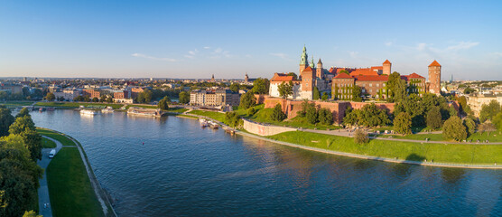 Krakow, Poland. Wide aerial panorama at sunset with Royal Wawel castle and cathedral. Vistula river banks, tourist boats, parks, promenades and walking people