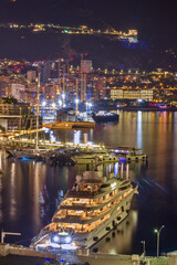 Luxury three-deck yachts in the night harbor of the Principality of Monaco, Cote d'Azur.