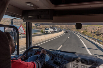 Truck driver driving on the highway, seen from inside the cab.