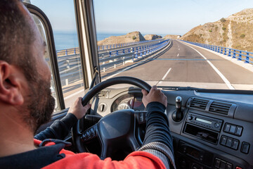 Truck driver driving on the highway, seen from inside the cab.