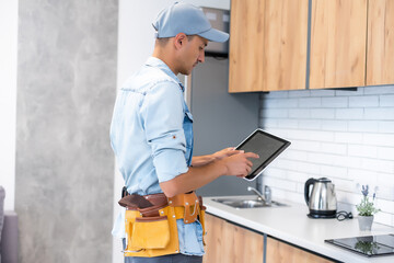 Male worker types on a tablet, kitchen renovation