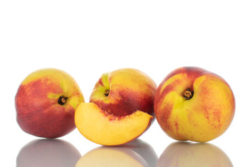 One slice of sweet nectarine in the foreground and three whole nectarines, close-up, isolated on white.