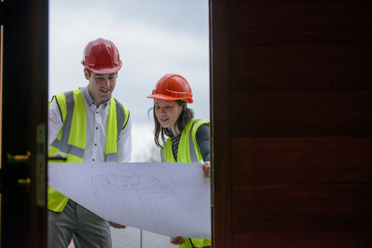 Architects in hard hats and reflective workwear inspecting plans