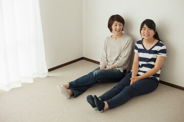 Mother and teenage daughter sitting on floor, portrait