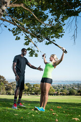 Young woman and trainer using lunge rope in park