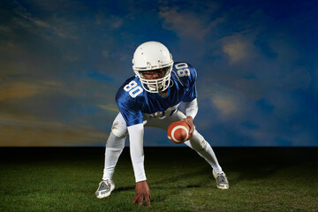 American football player leaning forward with hand on grass © Image Source Limited