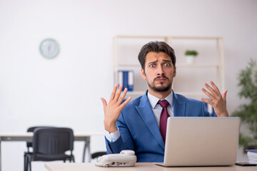 Young male employee unhappy with excessive work in the office