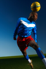 Young man heading football © Image Source Limited