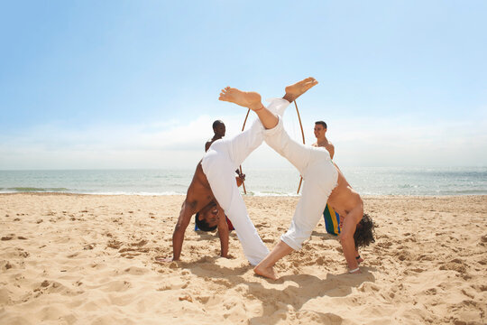 Men doing capoeira on beach