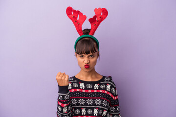 Young mixed race woman with reindeer hat celebrating Christmas isolated on purple background  showing fist to camera, aggressive facial expression.