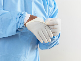 Mid section of surgeon wearing surgical scrubs putting on latex gloves