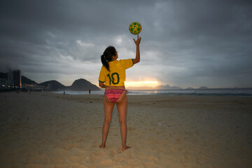 Mature woman balancing soccer ball on finger, Copacabana beach, Rio De Janeiro, Brazil