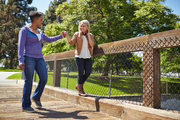 Naklejka premium Lesbian couple holding hands whilst strolling on park footbridge