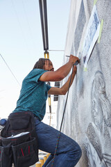 Male african american airbrush artist painting wall mural © Image Source Limited