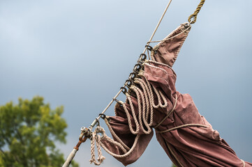 reefed sail on a historic sailing vessel against a dark sky, copy space