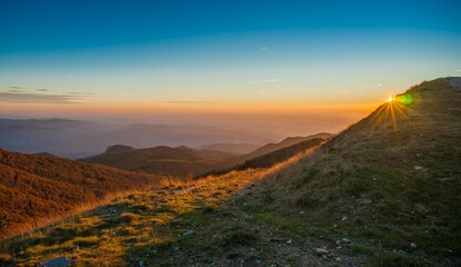 sunrise in the mountains with the sun rising from behind a hill